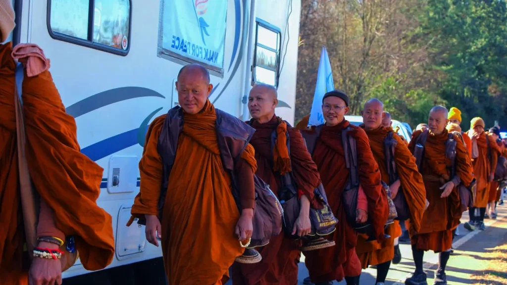 “People walking toward Buddhist monks during the Walk for Peace, symbolizing respect, harmony, and collective dedication to nonviolence.”