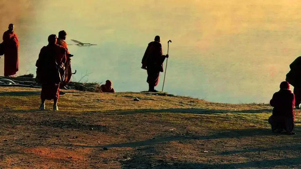 “Buddhist monks sitting on a riverbank in the afternoon after the Walk for Peace, symbolizing serenity, reflection, and peaceful devotion.”