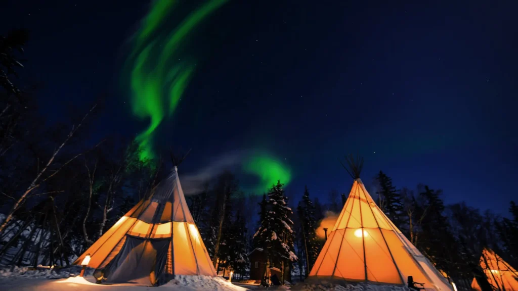  Green, purple, and pink streaks ripple above frozen landscapes