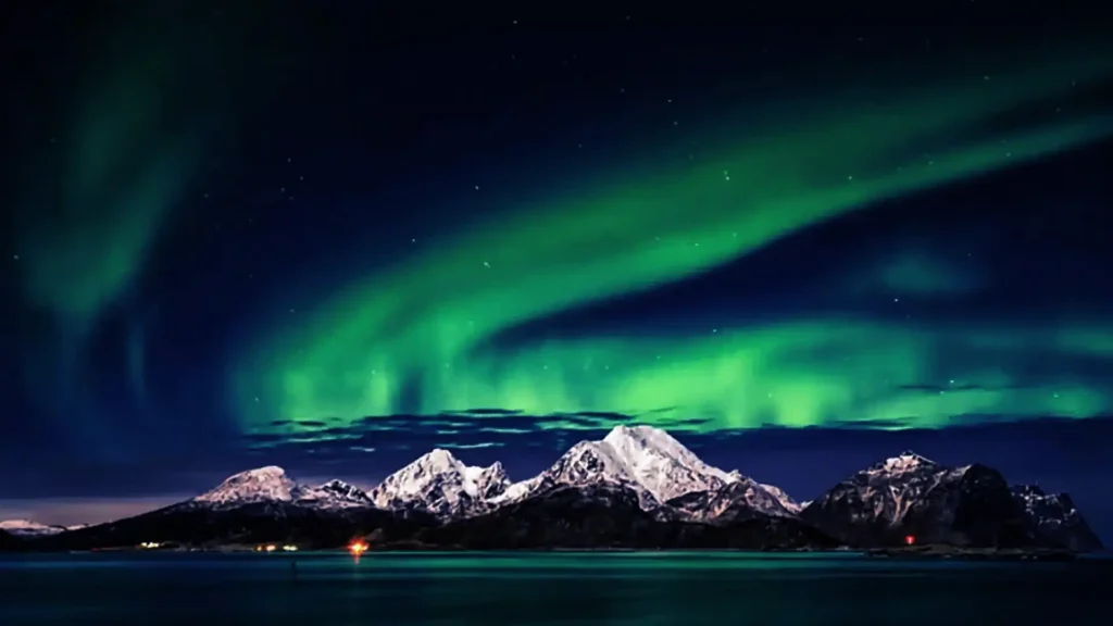  Green, purple, and pink streaks ripple above frozen landscapes